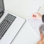 Frau am Laptop führt eine handschriftliche Checkliste